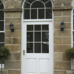 white wooden front door with arched wooden window