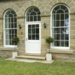 white wooden front door with arched wooden windows