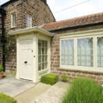 cream wooden front door area and arched windows