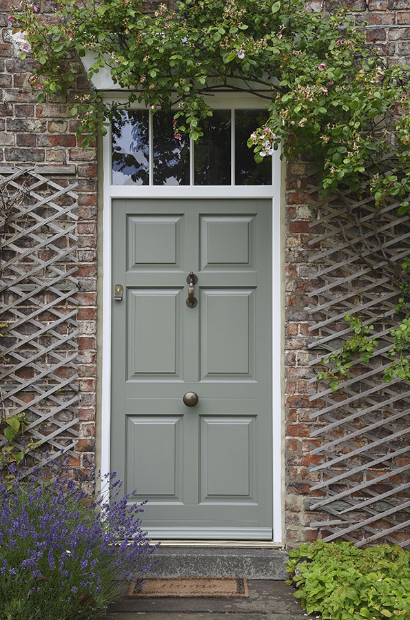 green wooden front door with bronze knob and knocker