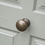 sage green wooden front door with brushed brass handle